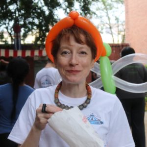 A Covenant House staff member eating popcorn with balloons on her head at Cov Carnival.